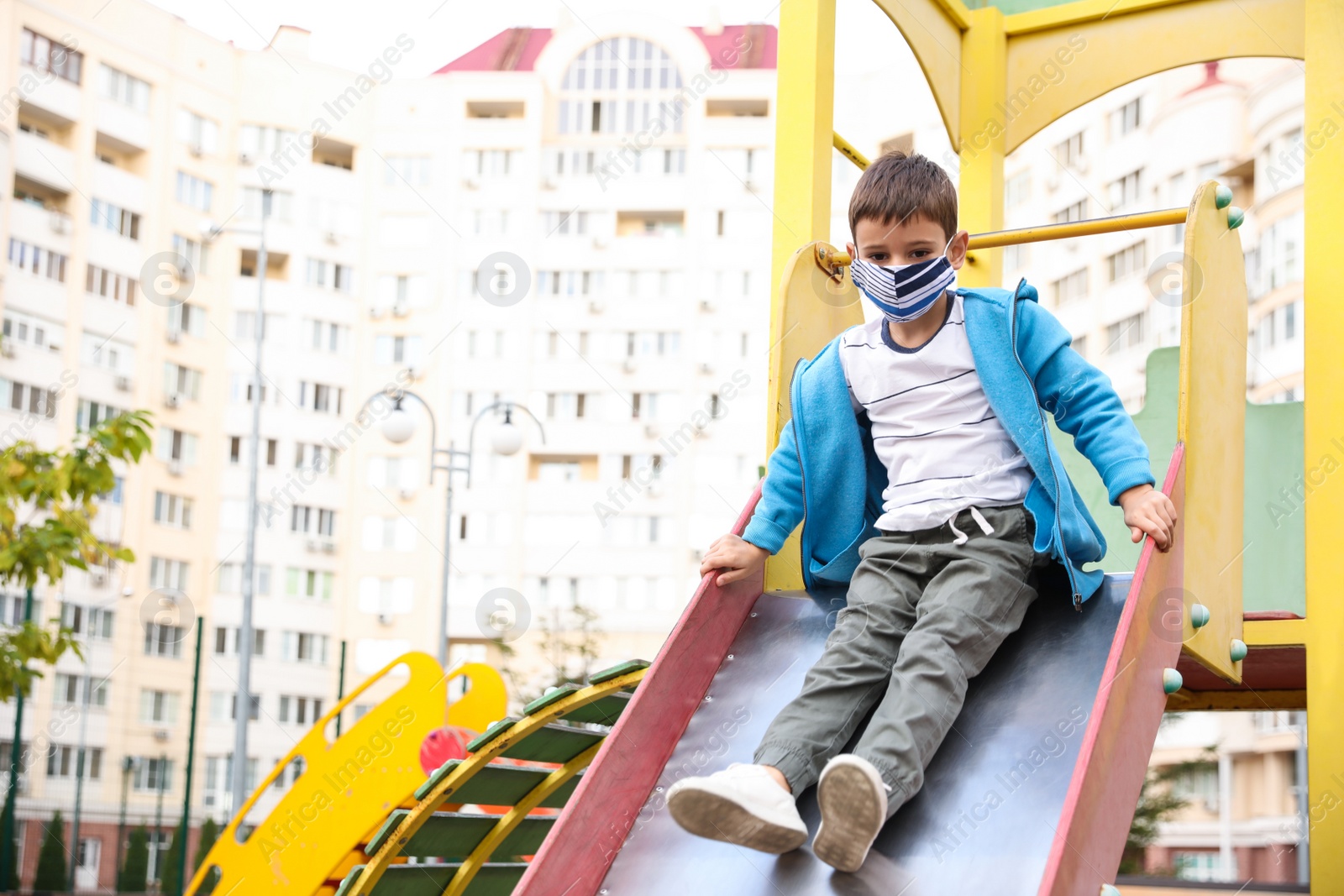 Photo of Little boy with medical face mask on playground during covid-19 quarantine