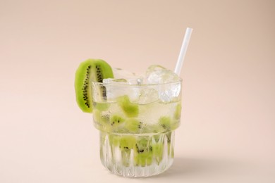 Photo of Glass of refreshing drink with kiwi on beige background