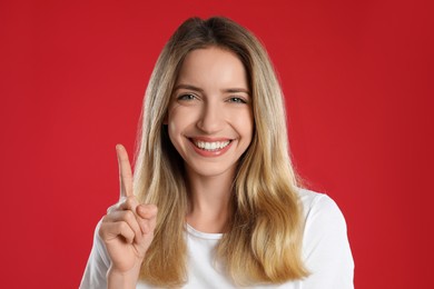 Photo of Woman showing number one with her hand on red background