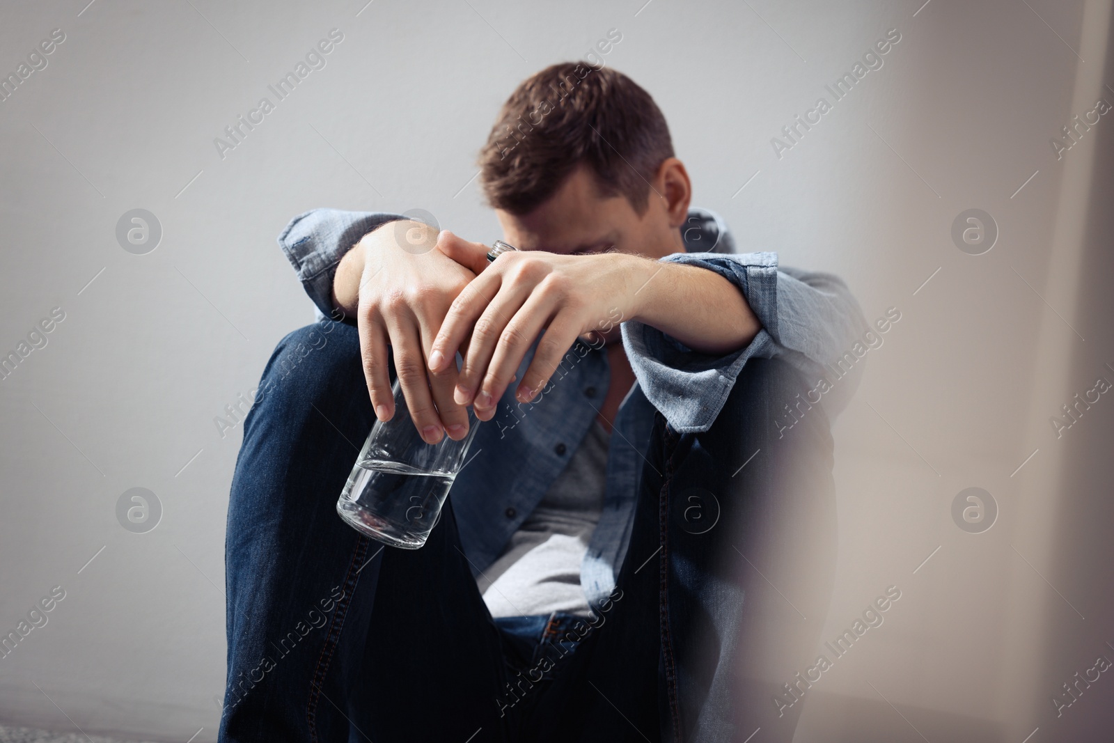 Photo of Addicted man with alcoholic drink near beige wall