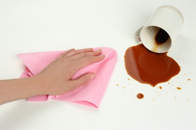 Photo of Woman cleaning spilled coffee on white background, closeup