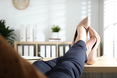 Photo of Lazy worker with feet on desk in office, closeup