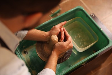 Man crafting with clay on potter's wheel, closeup