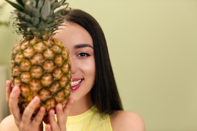 Photo of Young woman with fresh pineapple indoors, space for text. Exotic fruit