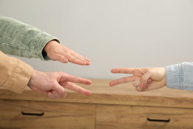 People playing rock, paper and scissors indoors, closeup