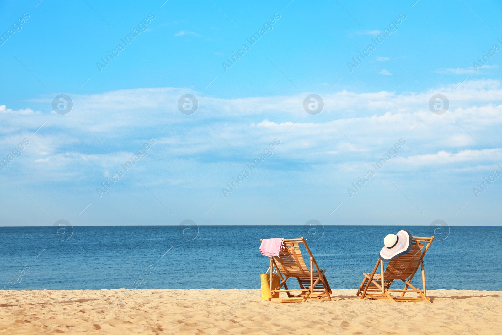 Photo of Empty wooden sunbeds and beach accessories on sandy shore