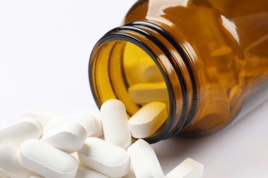 Photo of Bottle and vitamin pills on white background, closeup