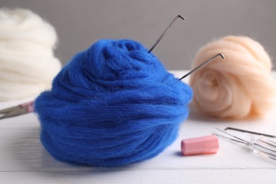 Photo of Blue felting wool and needles on white wooden table, closeup
