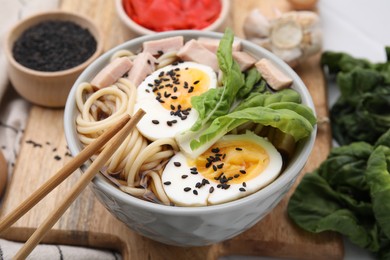 Photo of Bowl of delicious ramen with meat and egg on wooden board, closeup. Noodle soup