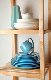 Photo of Shelving unit with set of dinnerware on light background. Interior element