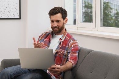 Photo of Bearded man having video chat on laptop indoors