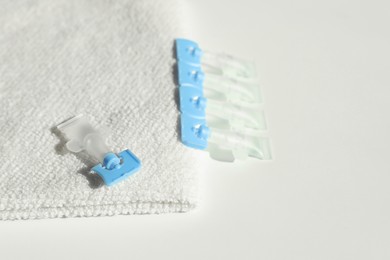 Single dose eye drops and towel on white table, closeup