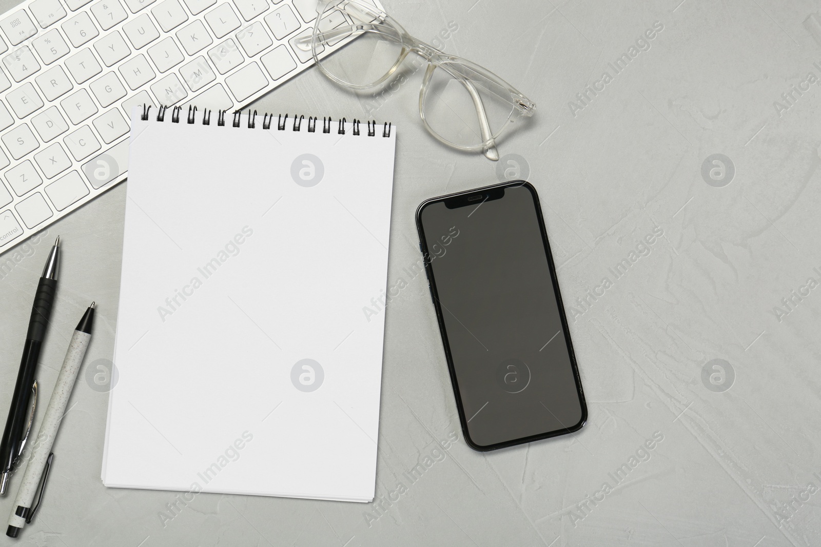 Photo of Flat lay composition with open notebook and smartphone on light grey table