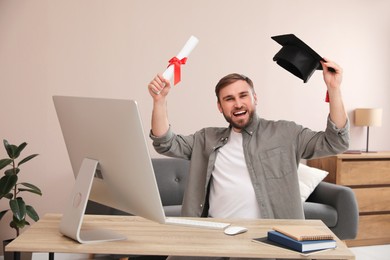 Emotional student with graduation hat and diploma at workplace in office