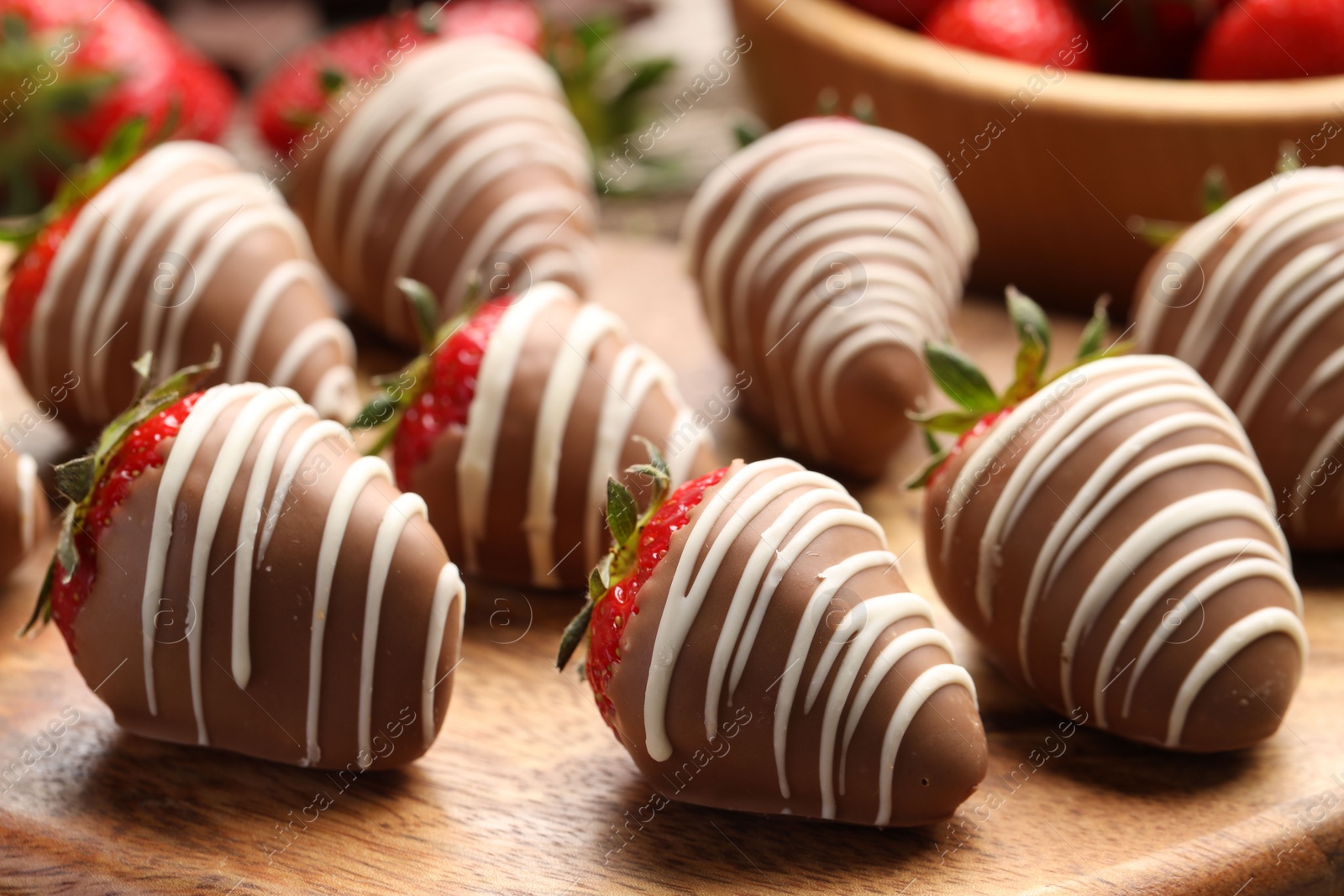 Photo of Delicious chocolate covered strawberries on wooden board, closeup