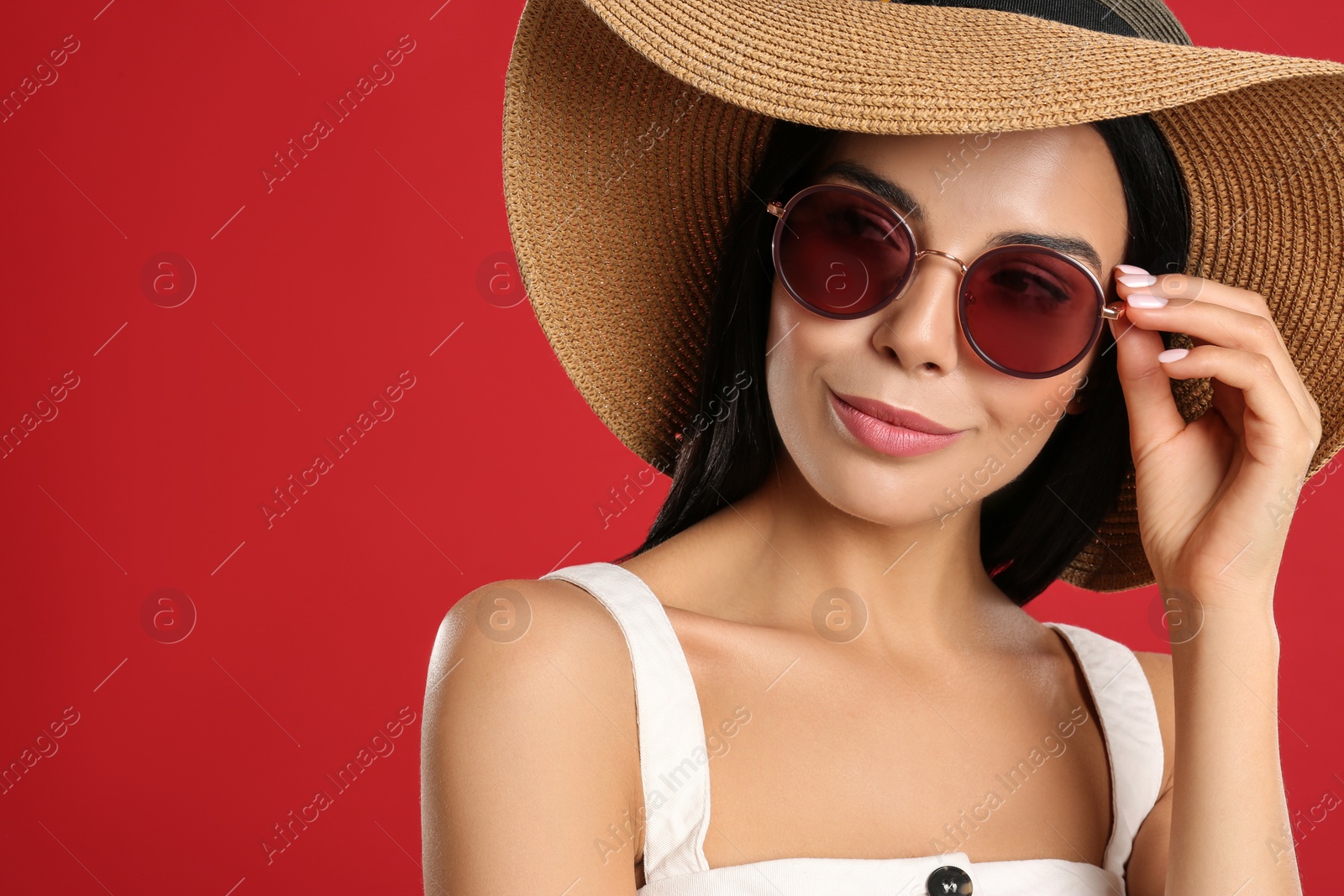 Photo of Beautiful woman wearing sunglasses on red background