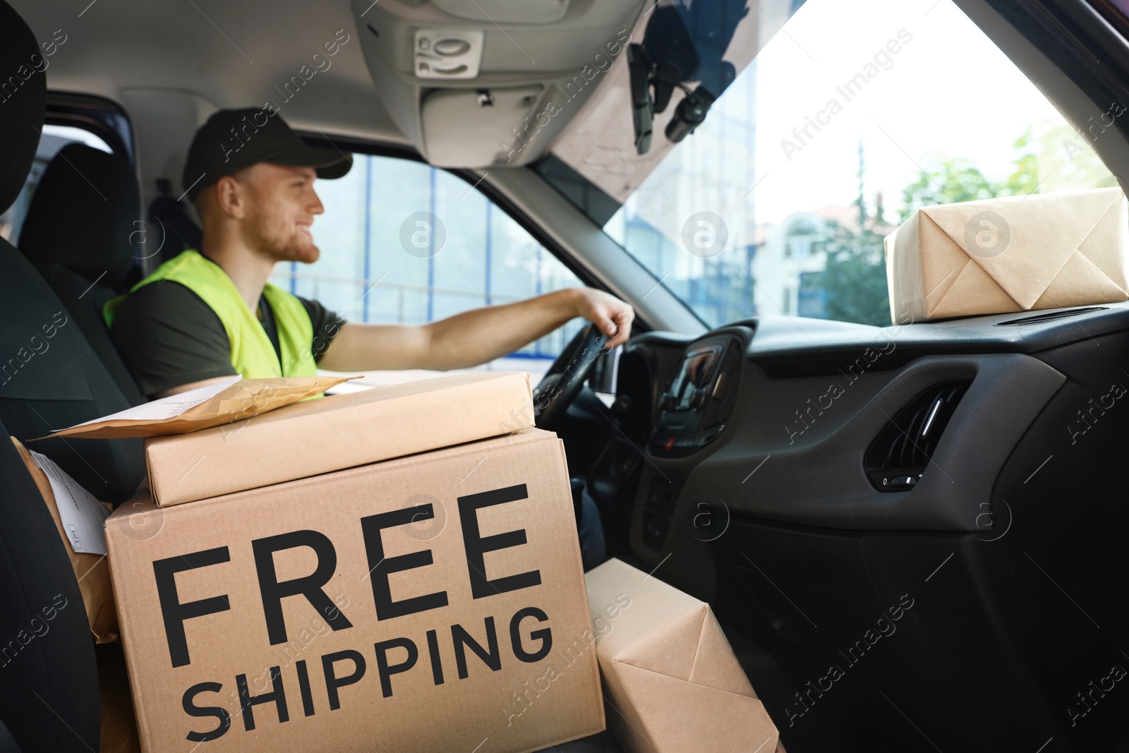 Image of Young courier with parcels in delivery car. Free shipping