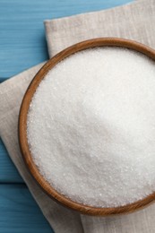 Photo of Granulated sugar in bowl on turquoise wooden table, top view