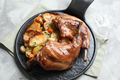 Tasty cooked rabbit meat with vegetables on light grey table, above view