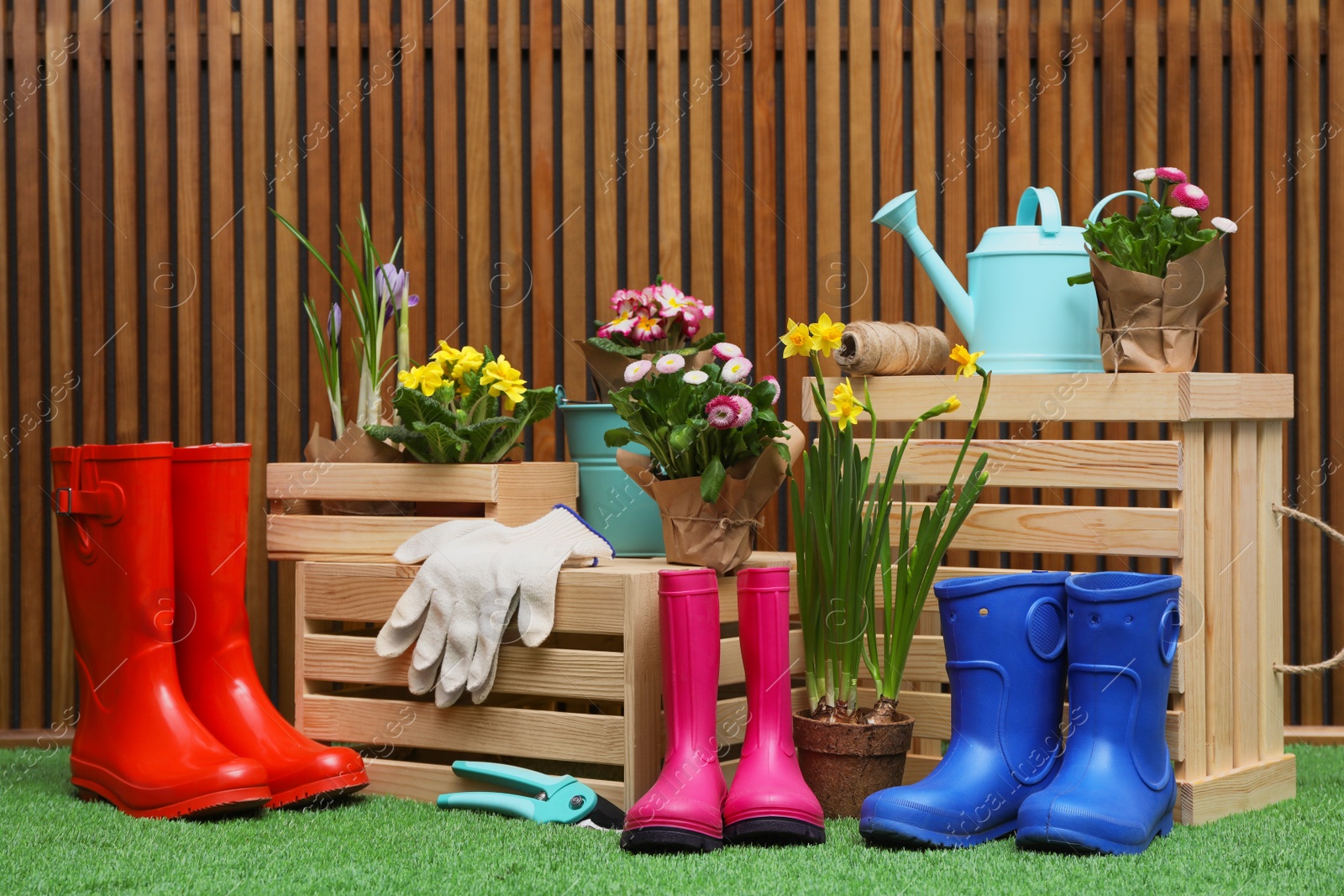 Photo of Composition with different gardening tools on artificial grass at wooden wall