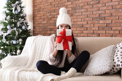 Photo of Beautiful young woman in hat with gift box at home. Christmas celebration