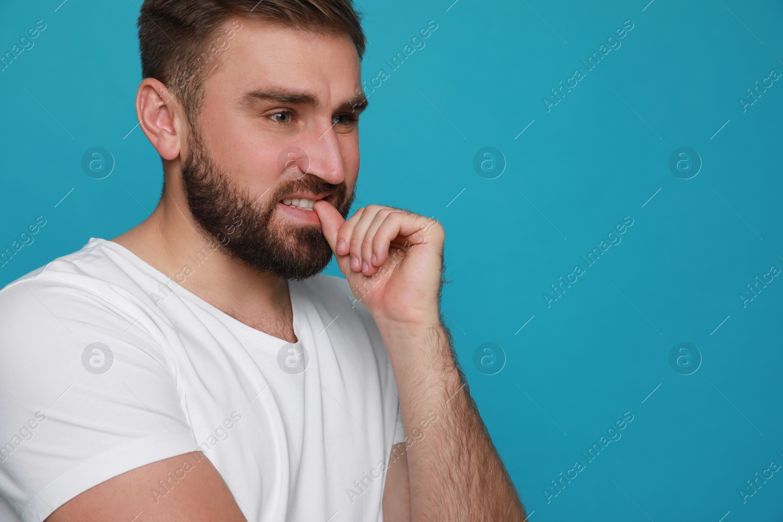 Photo of Man biting his nails on light blue background, space for text. Bad habit