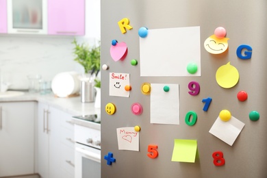 Photo of Many notes and empty sheets with magnets on refrigerator door in kitchen. Space for text