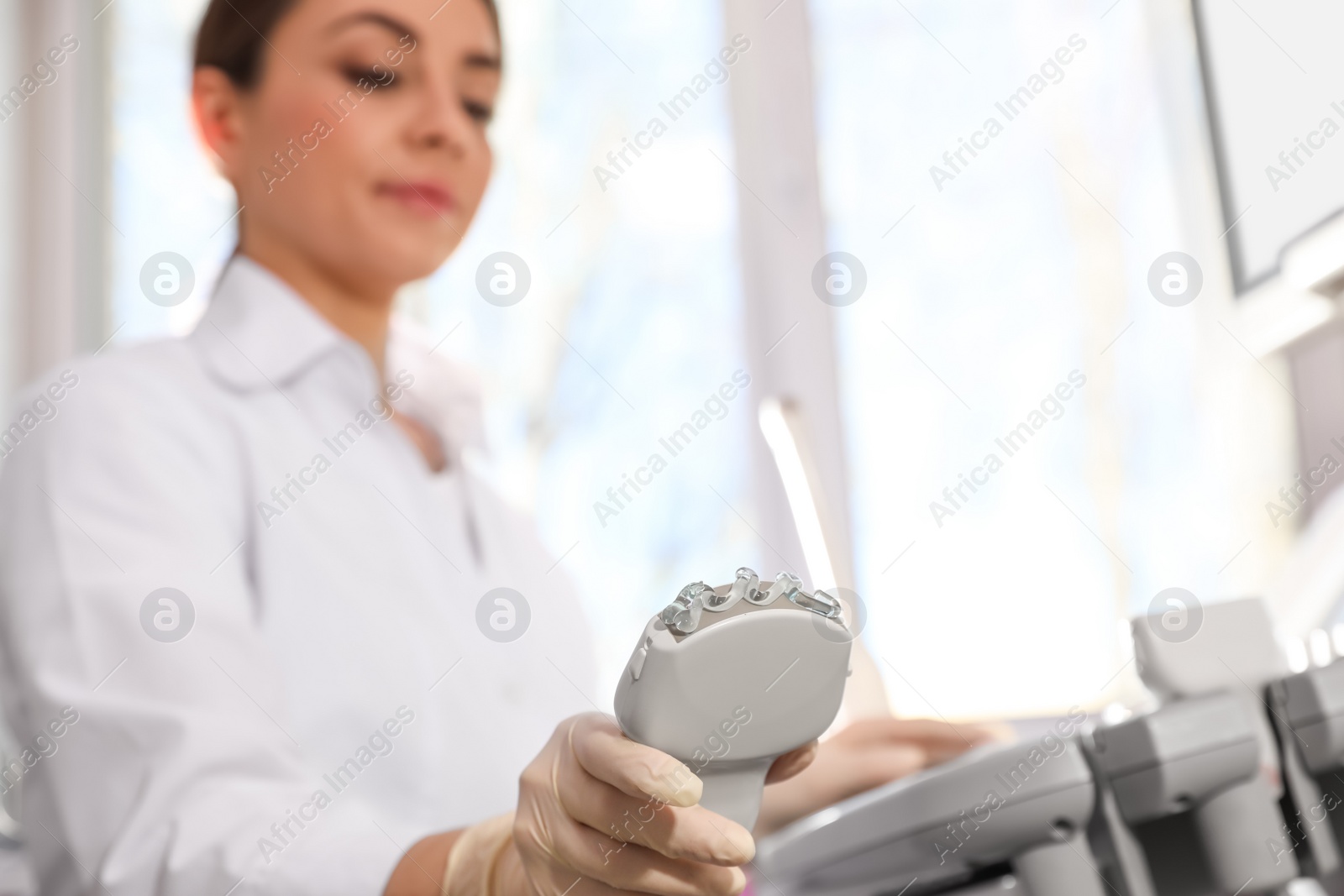 Photo of Sonographer holding ultrasound machine probe with gel in clinic