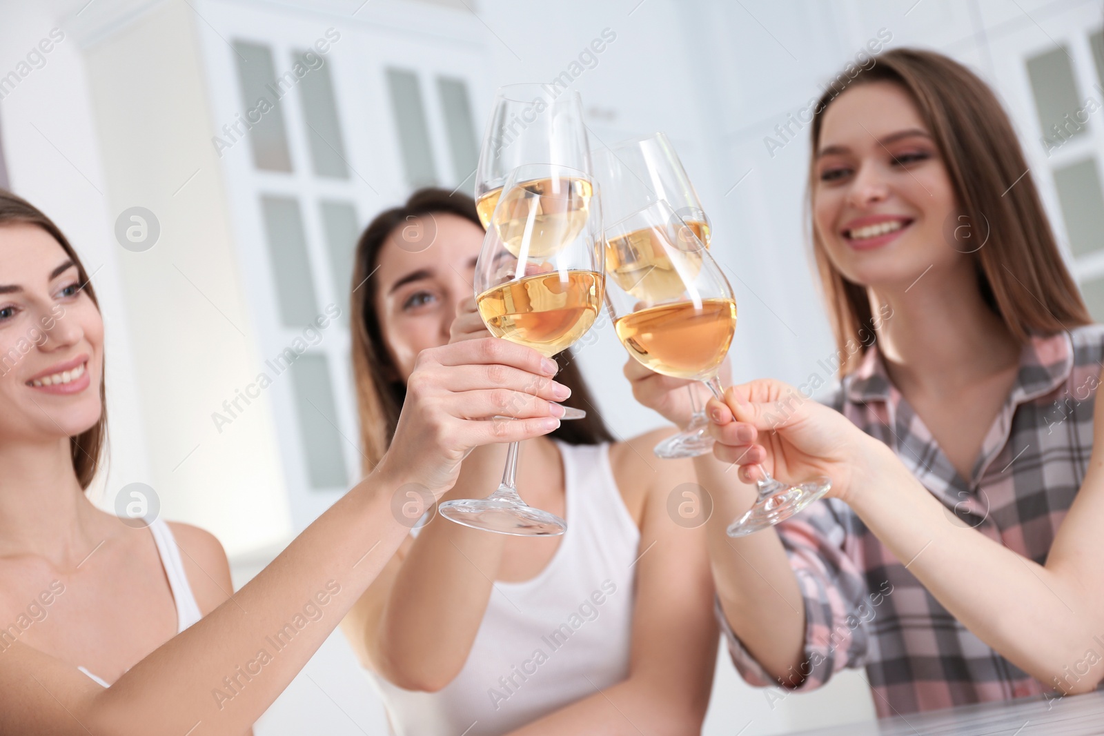 Photo of Beautiful young ladies toasting at home, focus on hands with glasses. Woman's Day