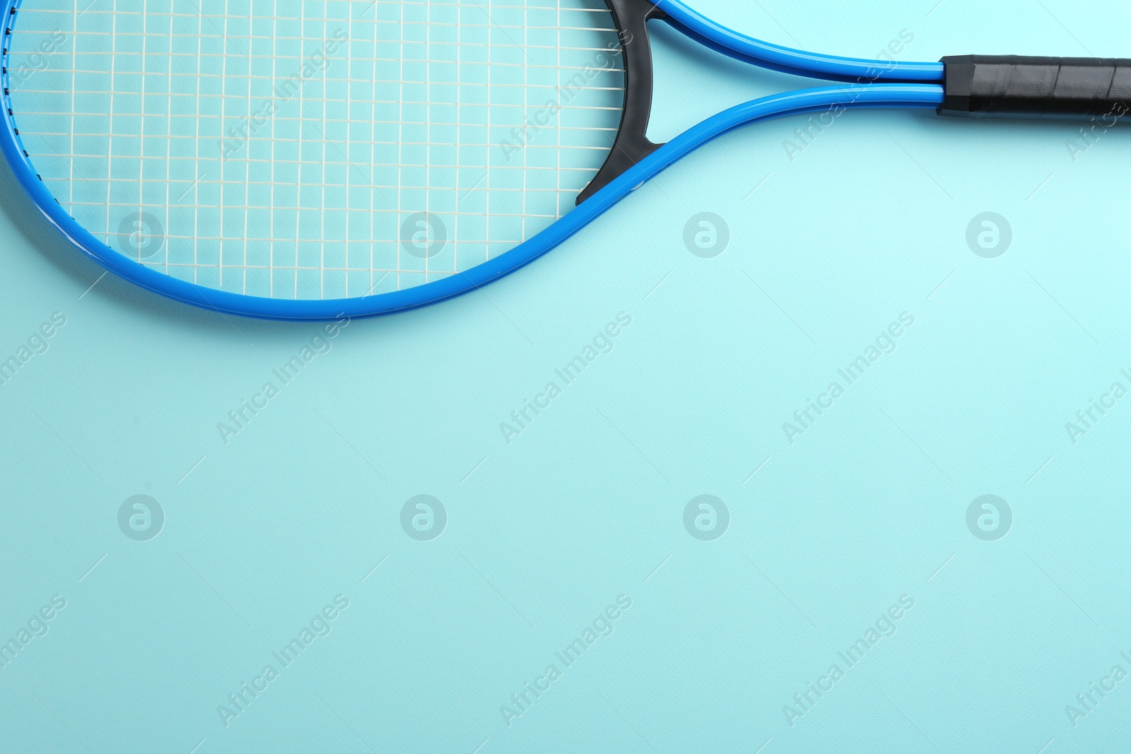 Photo of Tennis racket on light blue background, top view. Space for text