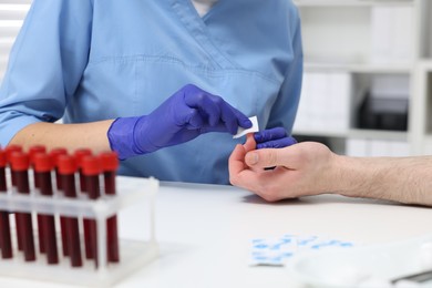 Laboratory testing. Doctor taking blood sample from patient at white table in hospital, closeup