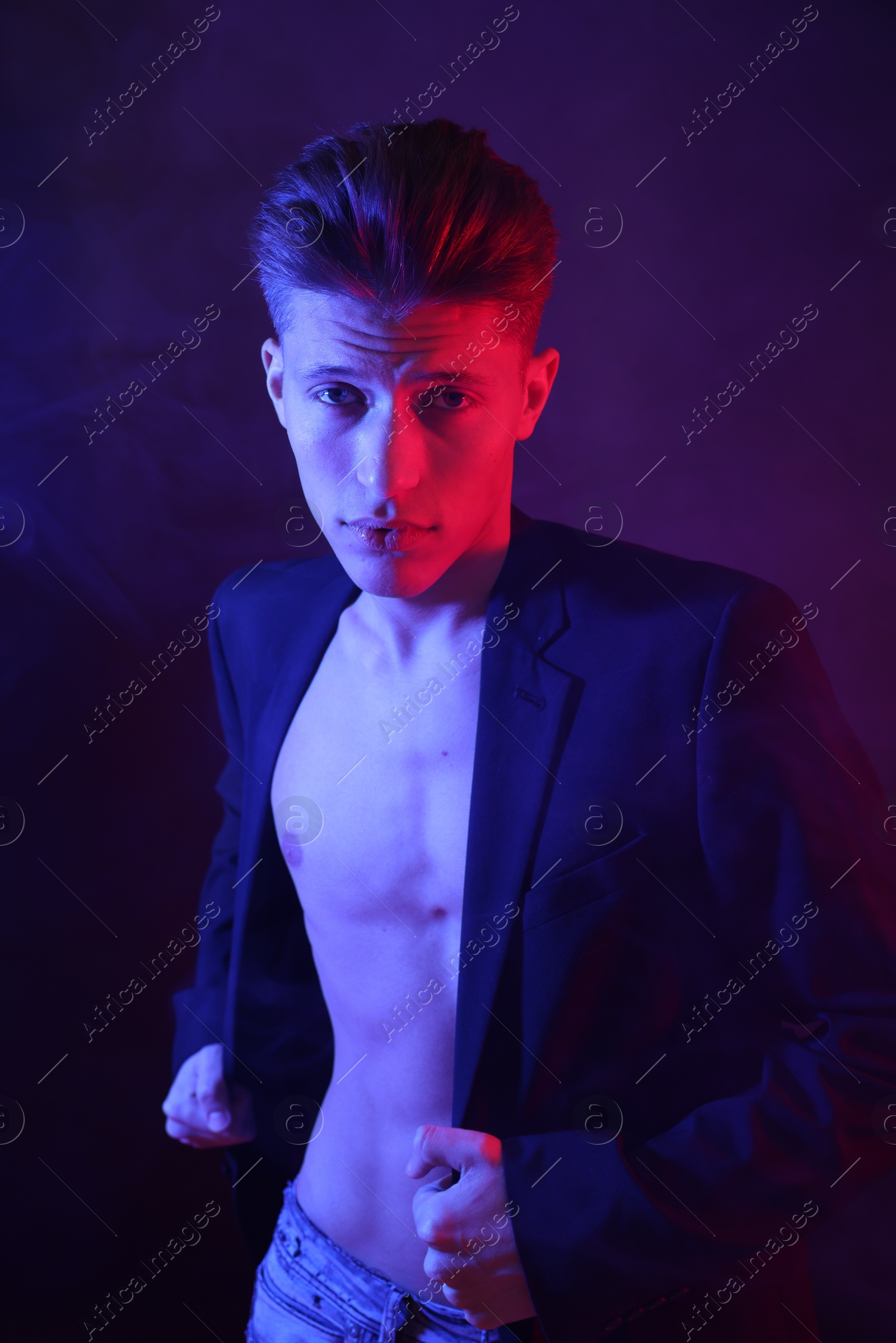 Photo of Sexy young man on dark background in neon lights