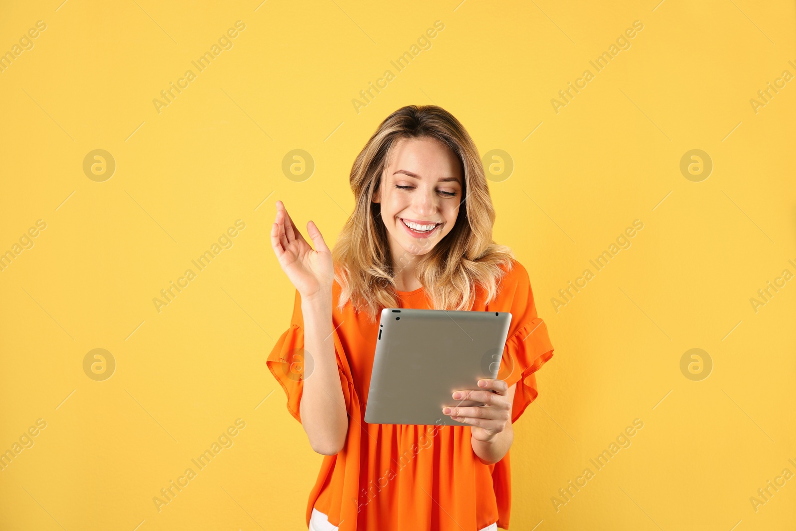 Photo of Woman using tablet for video chat on color background