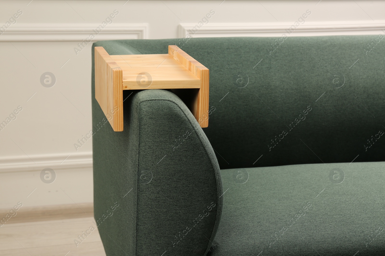 Photo of Wooden armrest table on sofa in room. Interior element