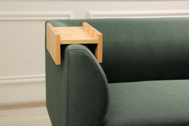 Photo of Wooden armrest table on sofa in room. Interior element