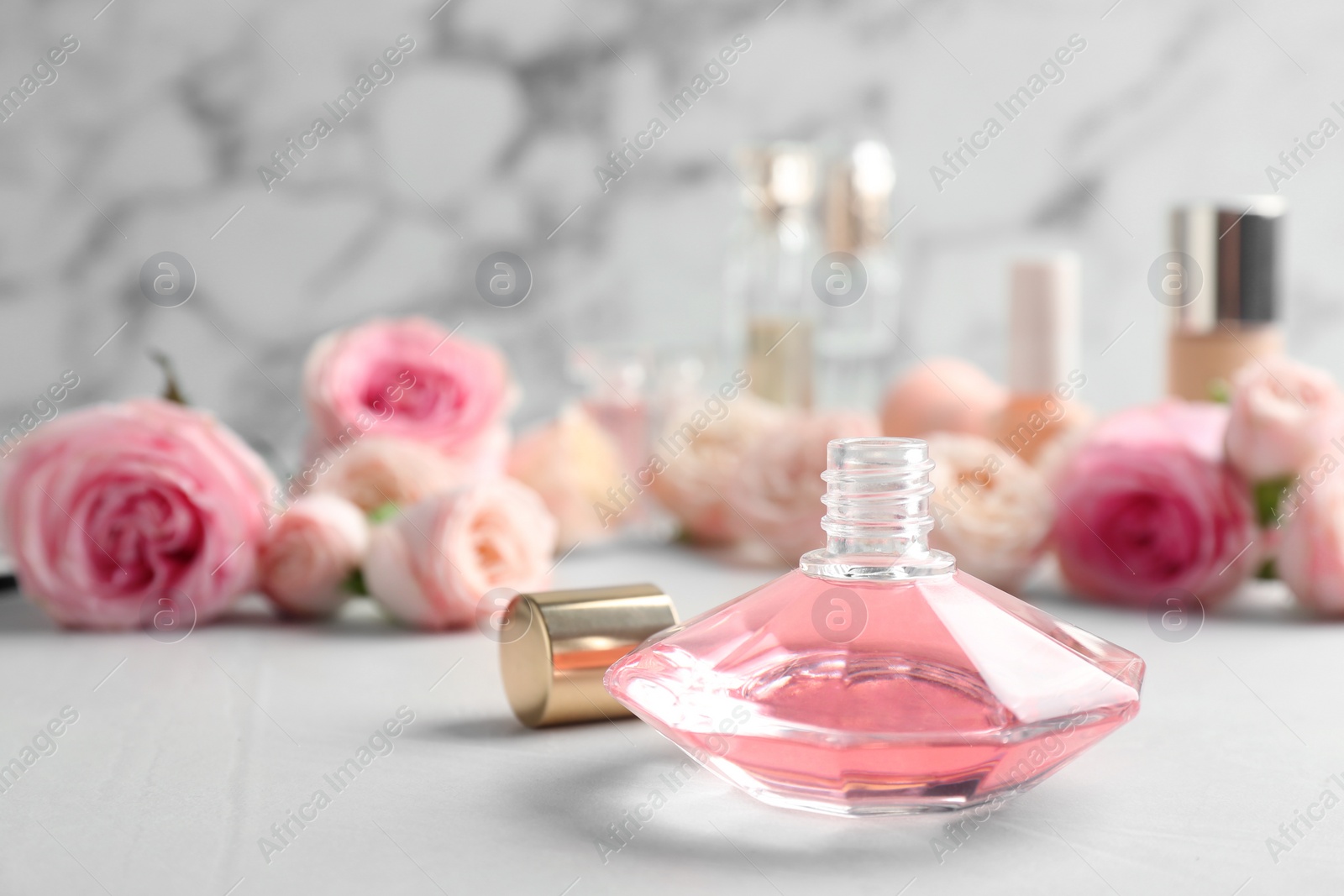 Photo of Bottle of perfume and roses on table against marble background. Space for text