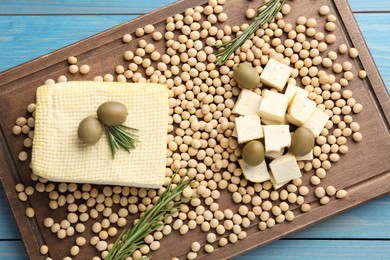 Photo of Cut tofu, olives and soya beans on blue wooden table, top view