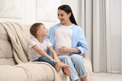 Happy pregnant woman spending time with her son at home