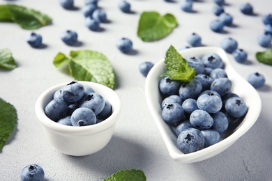 Photo of Juicy blueberries and green leaves on color table
