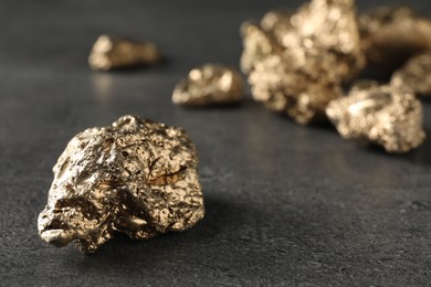 Photo of Shiny gold nugget on grey surface, closeup. Space for text