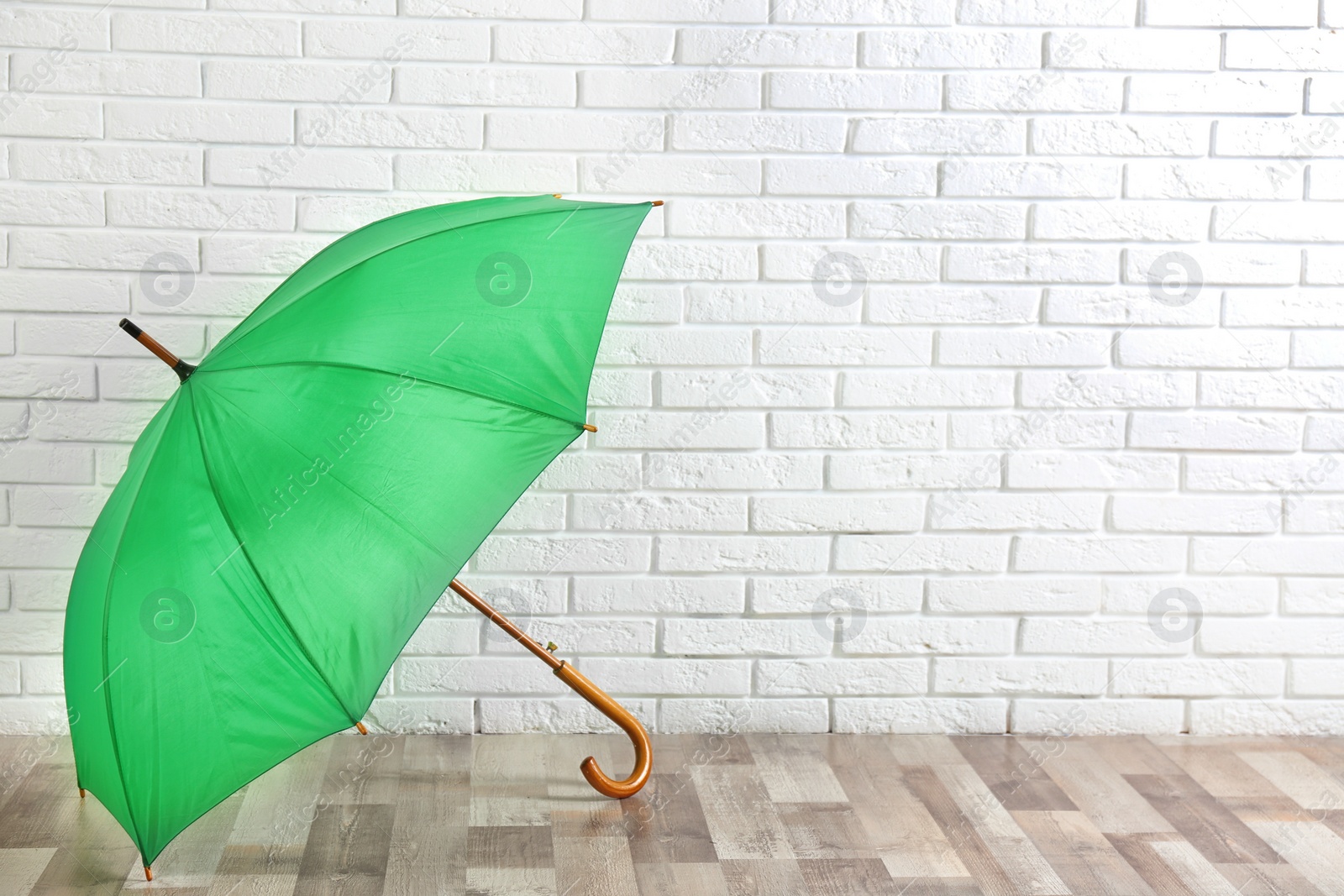 Photo of Beautiful green umbrella near white brick wall. Space for text