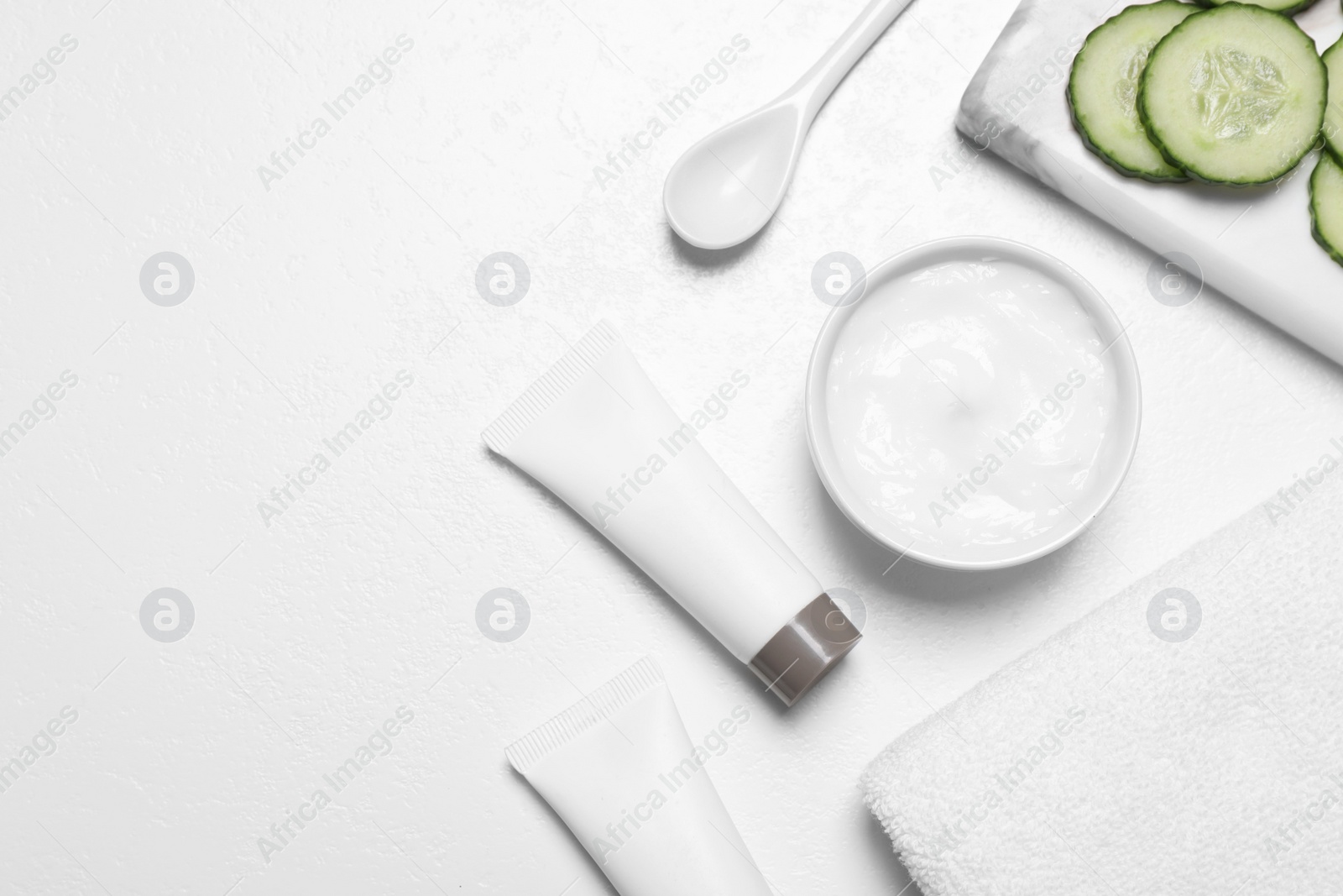 Photo of Flat lay composition with cream and cucumber slices on white table. Space for text