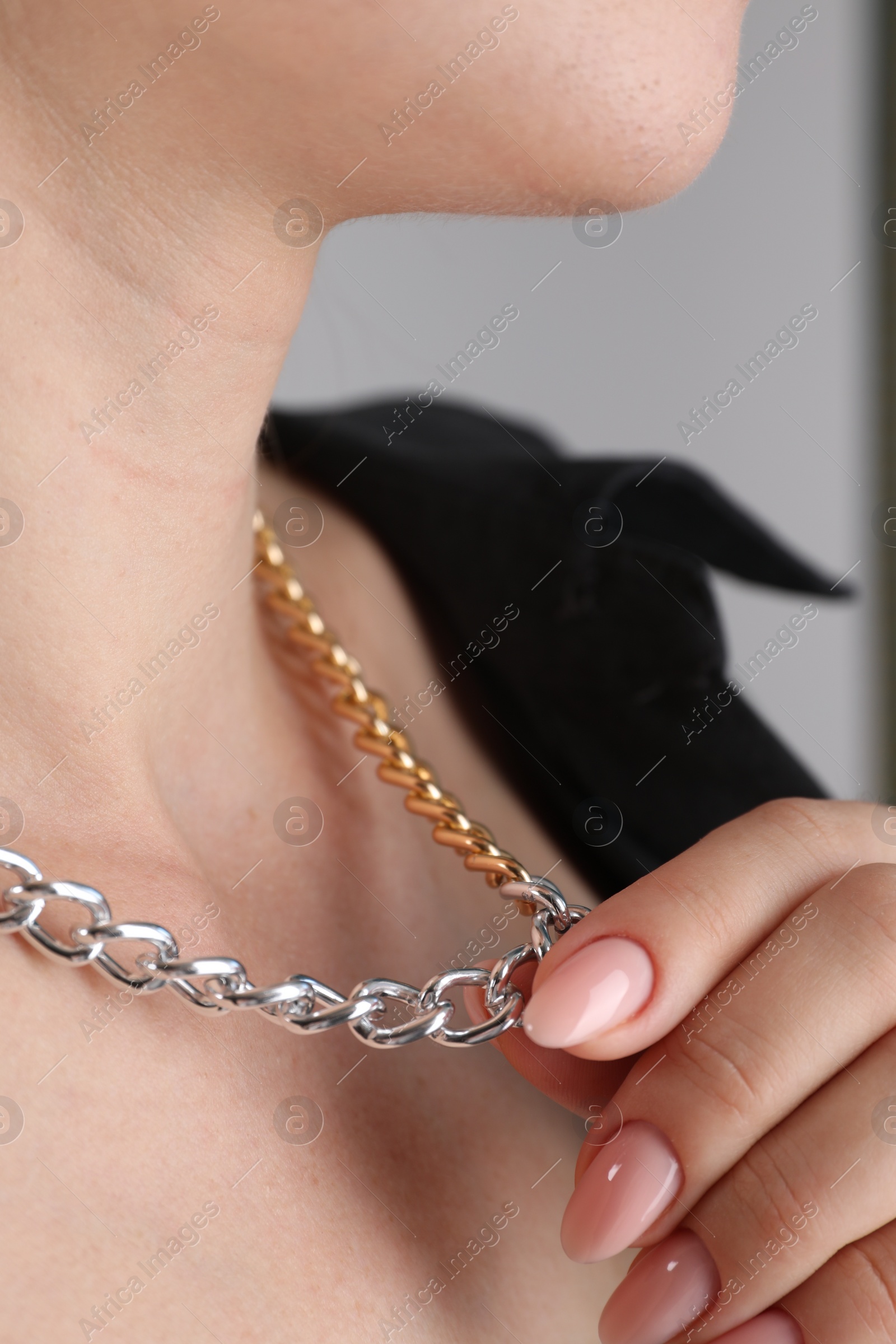 Photo of Woman wearing metal chain, closeup. Luxury jewelry