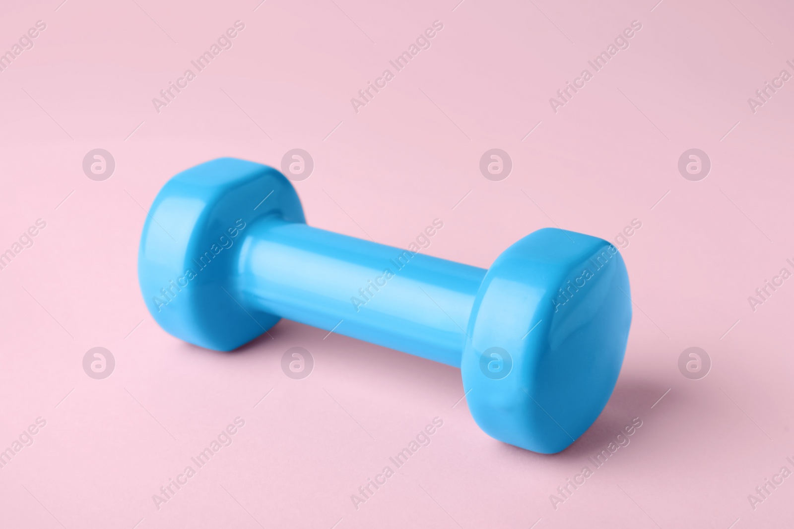 Photo of One turquoise dumbbell on light pink background