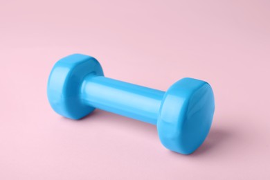 Photo of One turquoise dumbbell on light pink background