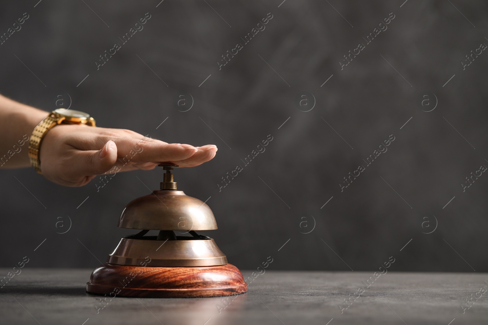 Photo of Woman ringing hotel service bell at table, closeup. Space for text