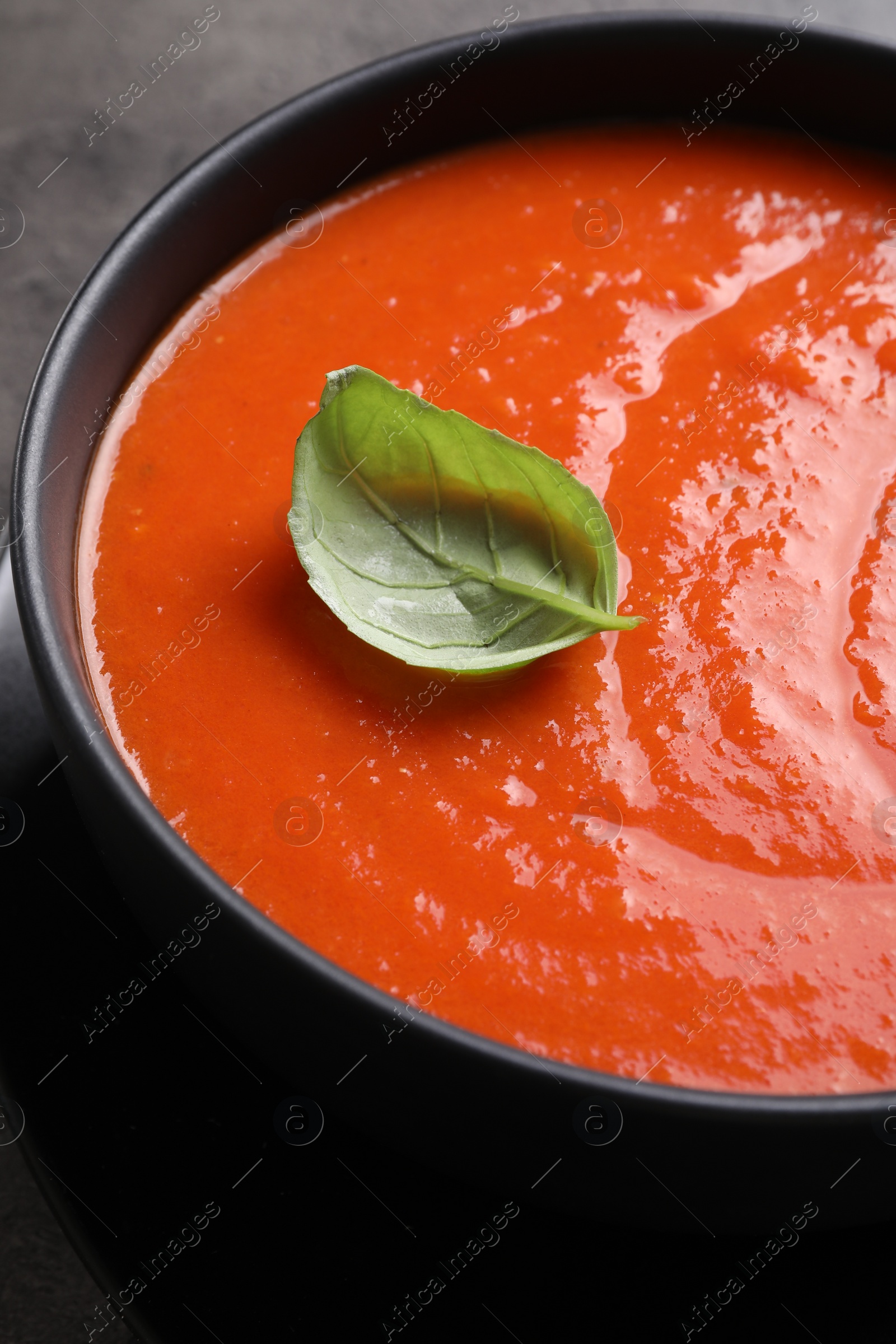 Photo of Delicious tomato cream soup in bowl on grey table, closeup