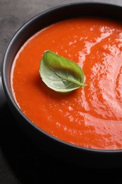 Photo of Delicious tomato cream soup in bowl on grey table, closeup