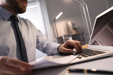 Businessman working with documents at wooden desk in office, closeup