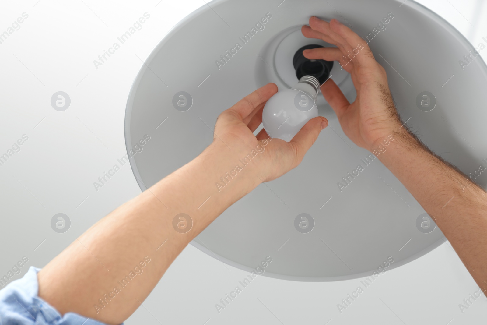 Photo of Man changing light bulb in lamp indoors, closeup